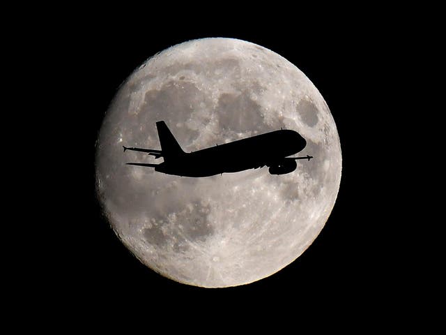 A plane passes in front of the moon on its approach to London Heathrow airport