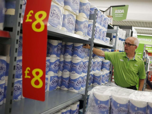An employee stocks toilet paper along an aisle of an Asda store in Kendal, northwest England.