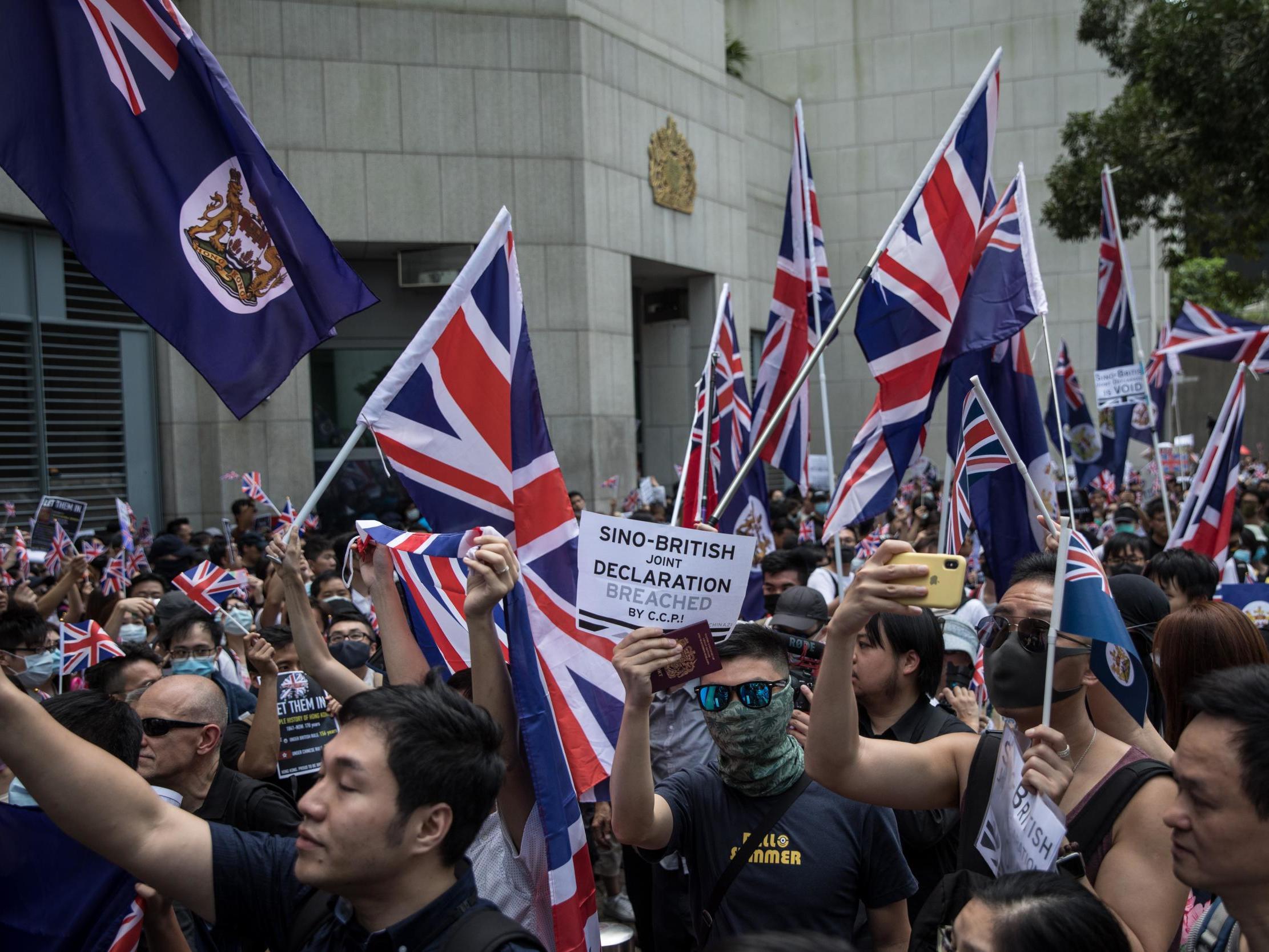 Pro-democracy protesters wave flags and chant slogans outside the UK embassy