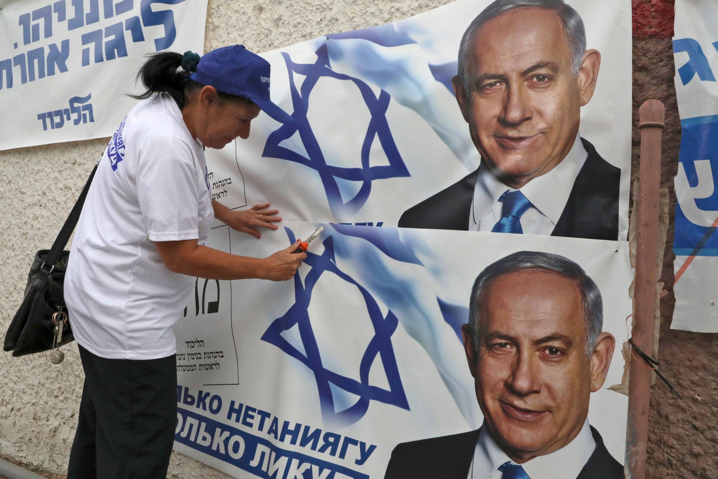 A woman places electoral banners for the Likud party showing chairman and Israeli Prime Minister Benjamin Netanyahu in the southern Israeli city of Beersheva on September 15, 2019