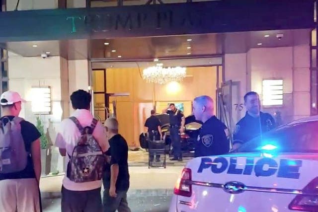 People and police officers stand outside Trump Plaza after a car crashed into the building's lobby