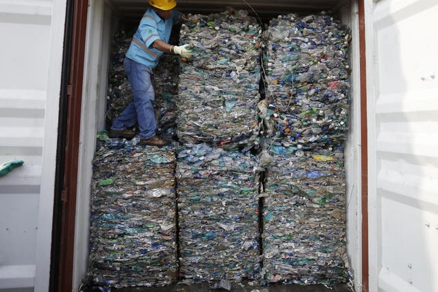 A worker stands inside a container full of plastic waste at Tanjung Priok port in Jakarta, Indonesia