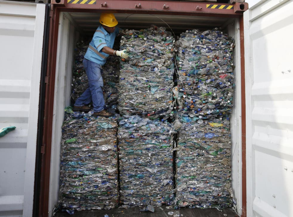 A worker stands inside a container full of plastic waste at Tanjung Priok port in Jakarta, Indonesia