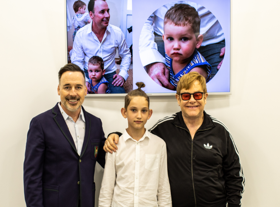 Sir Elton and David Furnish in Kiev with a Ukrainian boy who had received help from one of EJAF's projects as a baby, 15 years previously, and pictured behind them