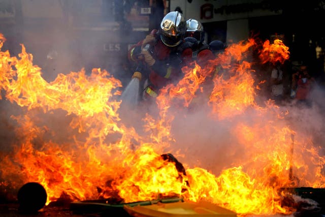 Firefighters extinguish a barricade during a protest over climate change in Paris