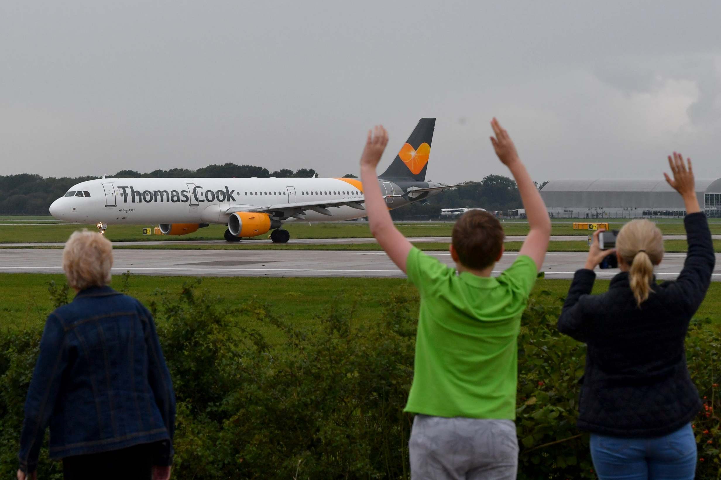  The pilot's family members wave as a Thomas Cook aircraft departs from Manchester Airport