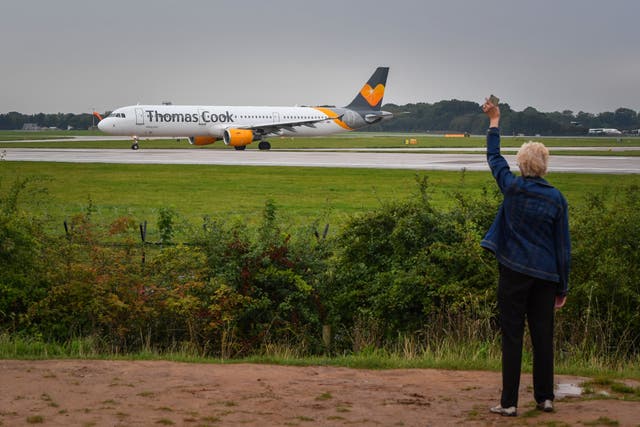 A woman waves as a Thomas Cook aircraft departs from Terminal 1 at Manchester Airport