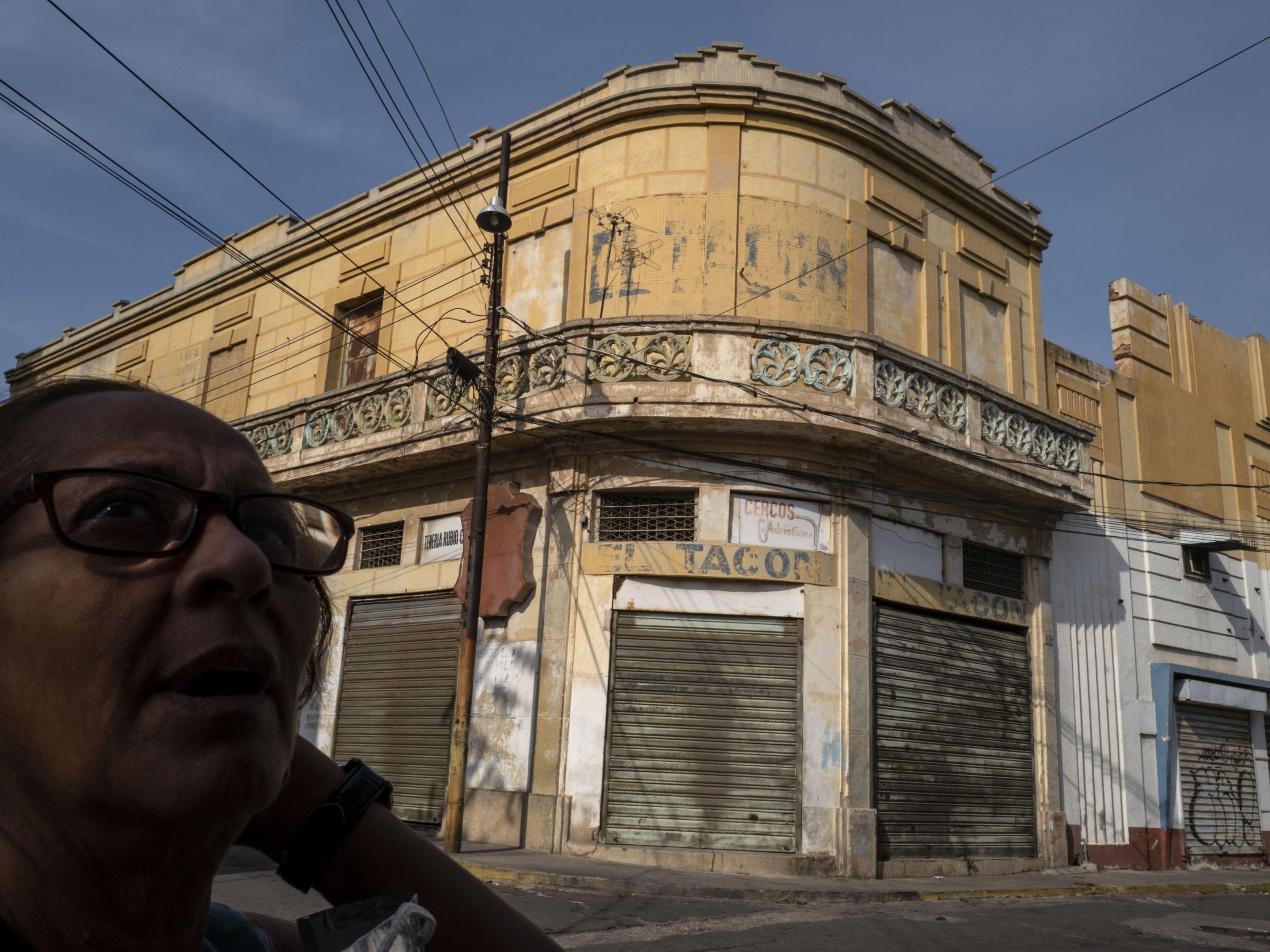 A woman passes a group of shuttered businesses in central Maracaibo, Venezuela