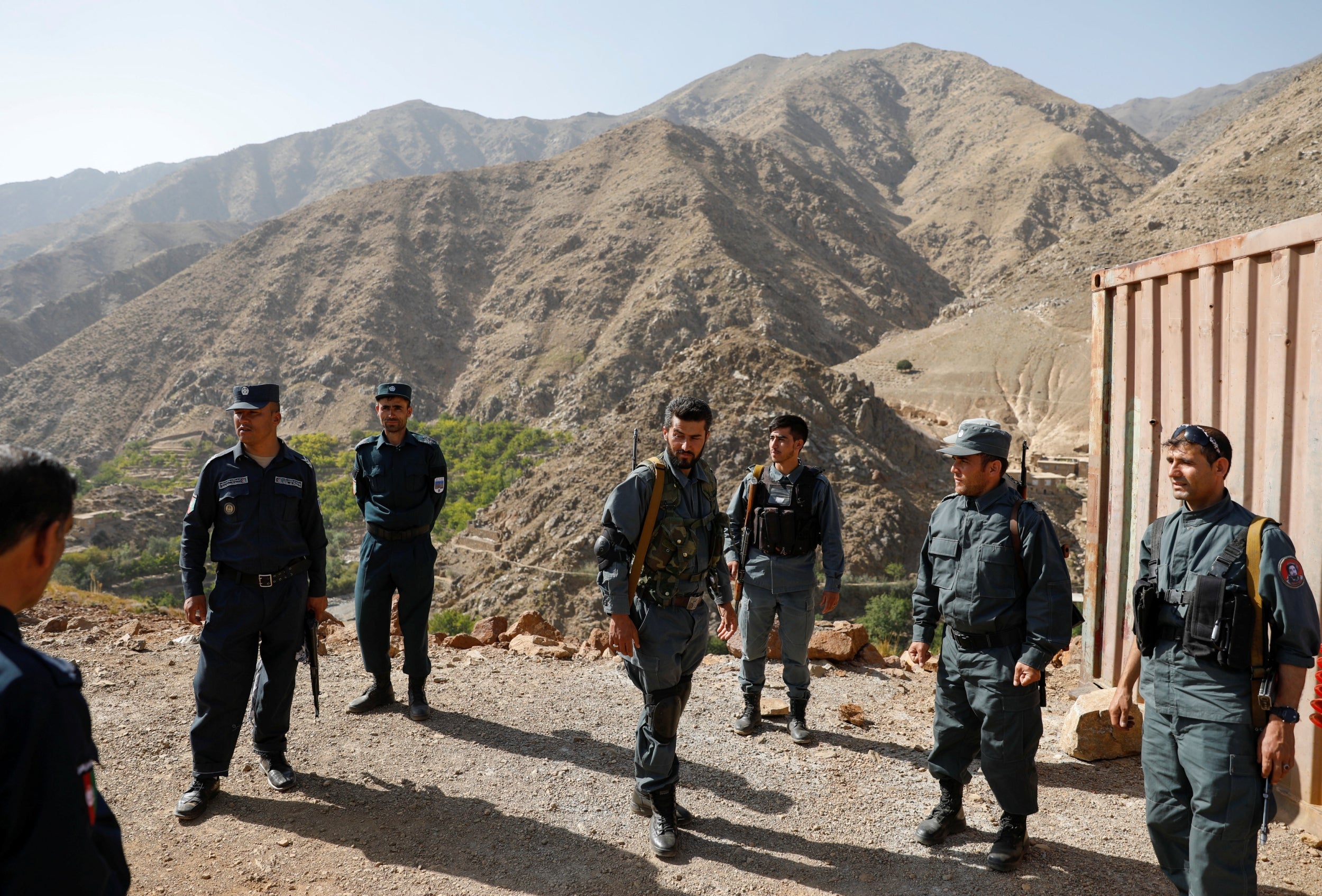 Afghan policemen keep watch as others carry election material to polling stations inaccessible by road, in Shutul, Panjshir province, on Friday