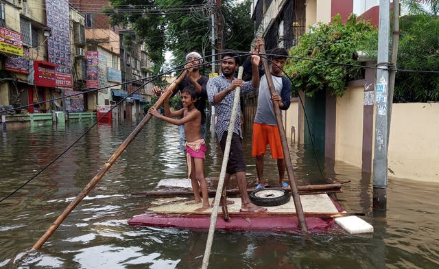 People use a makeshift raft to move out of a flooded neighbourhood in Patna