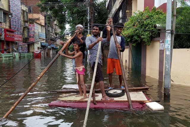 People use a makeshift raft to move out of a flooded neighbourhood in Patna