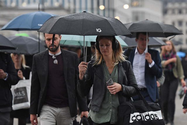 Commuters cross London Bridge as parts of Britain brace for two more days of heavy downpours, 30 September, 2019.