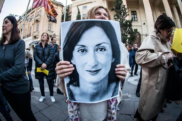 A protester holds a poster of Daphne Caruana Galizia, assassinated in a car bomb attack in 2017, during a vigil demanding justice