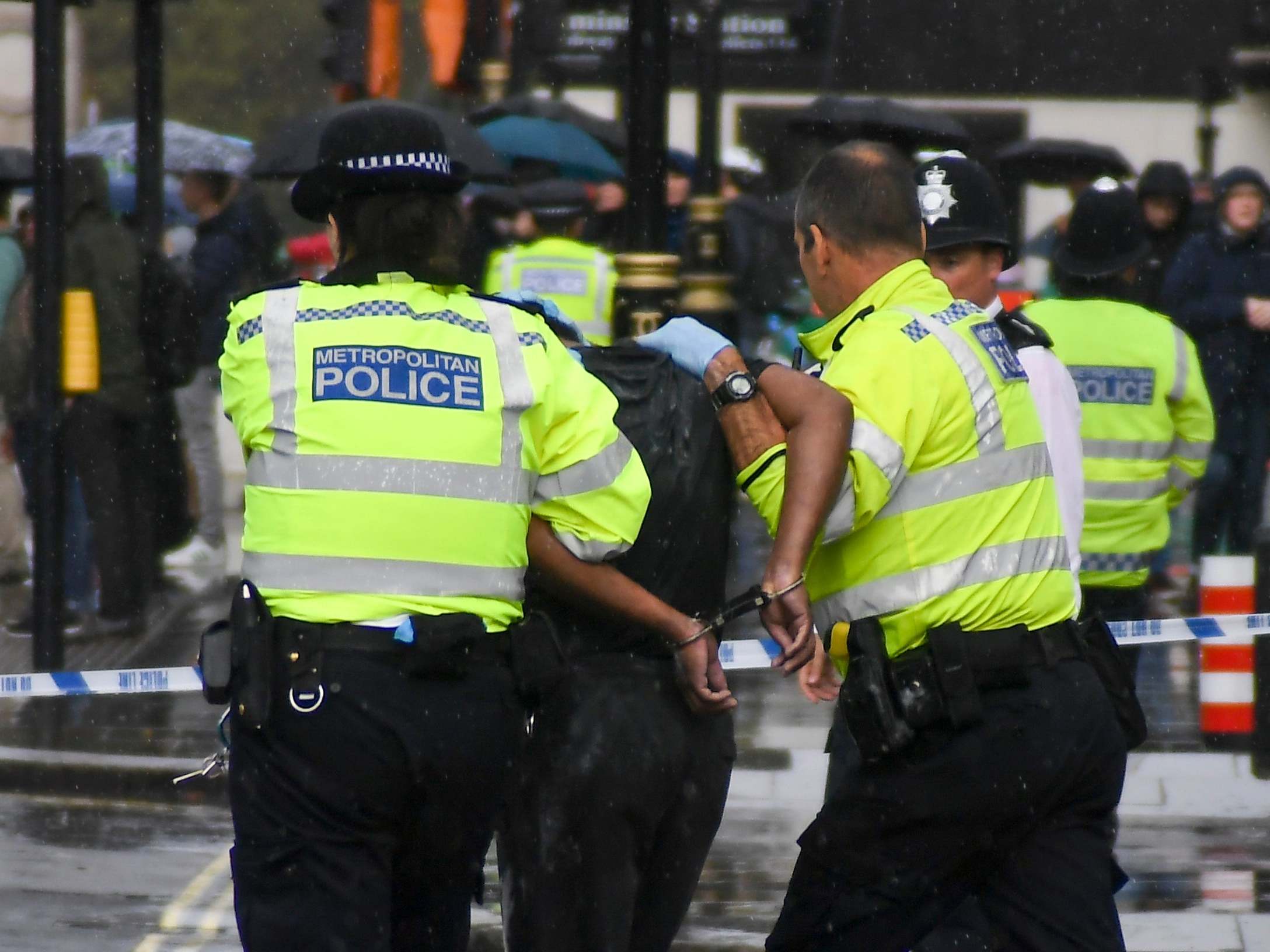 Police and paramedics take away a handcuffed man who doused himself in what is believed to have been petrol outside parliament