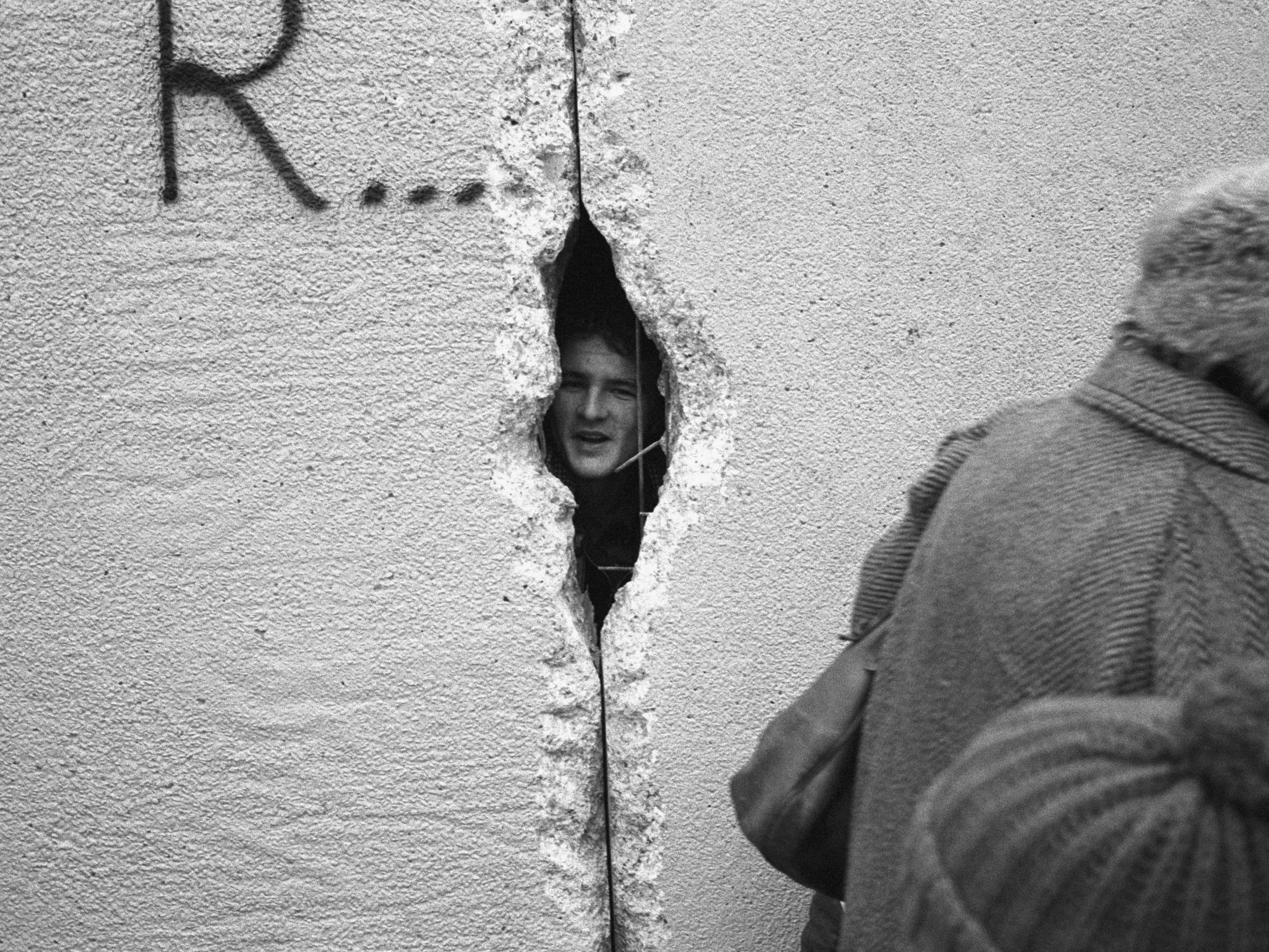 A young man peers into East Berlin through a hole in the Berlin Wall in 1989