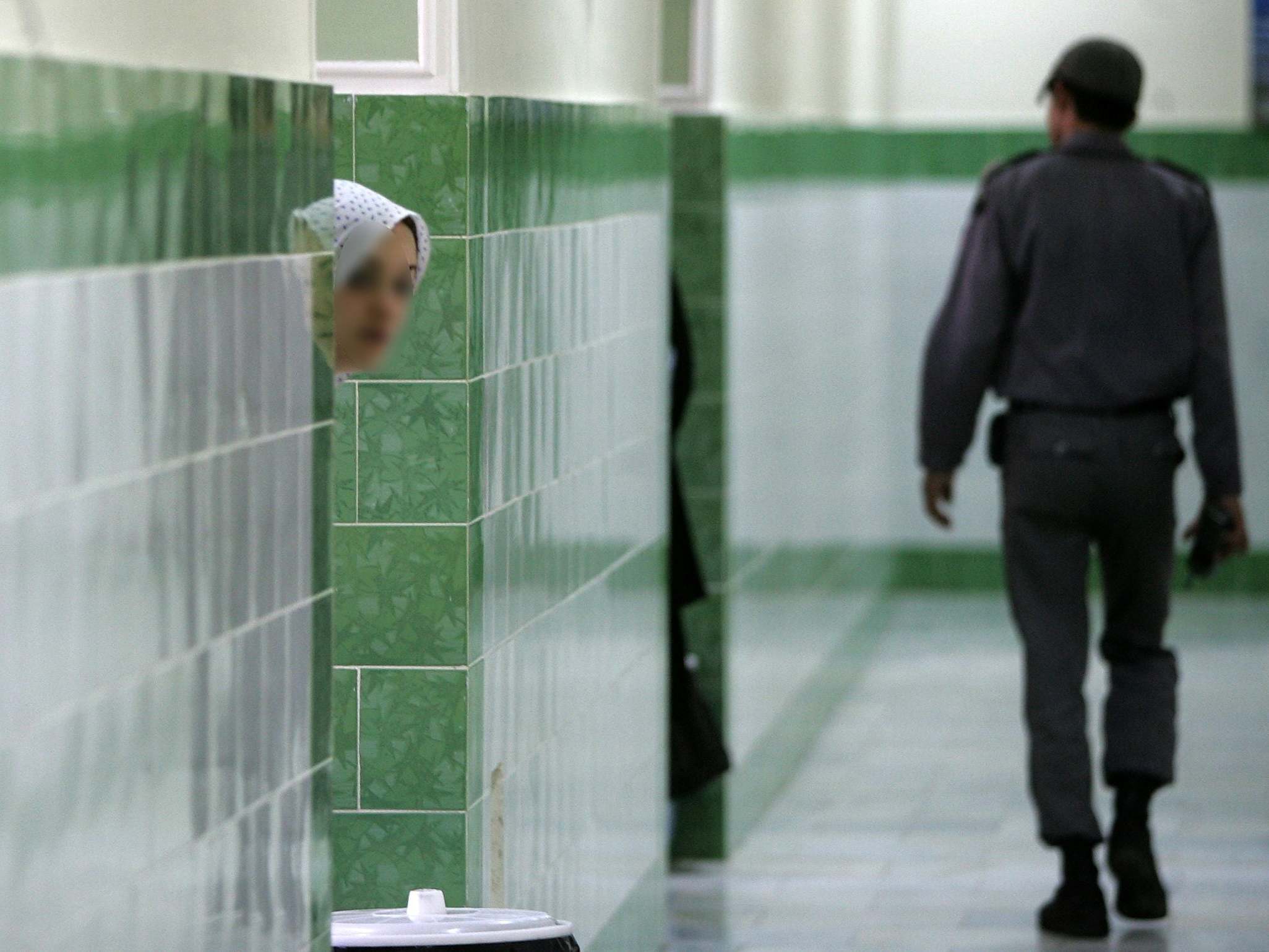 A prison guard walks by an inmate at the infamous Evin prison, north of Tehran, where several British citizens are reportedly being held on spying charges