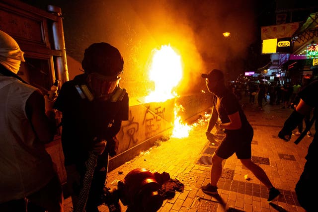 An anti-government protester throws a molotov cocktail to sets a fire at the Sham Shui Po Station