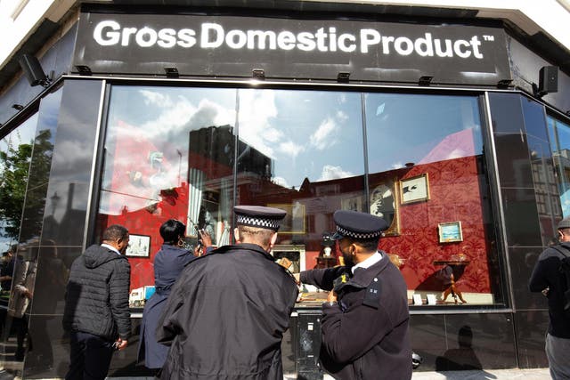 Police officers and members of the public gather outside Gross Domestic Product, a homeware store that is being launched in South London by Banksy.