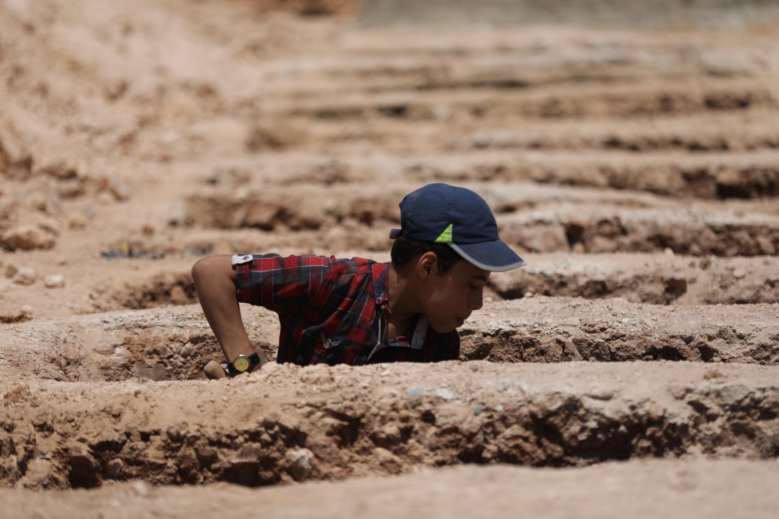 Fifteen-year-old Yazan digs a grave in the cemetery where he works with his brother on the outskirts of Idlib (Khalil Ashawi/Save the Children)