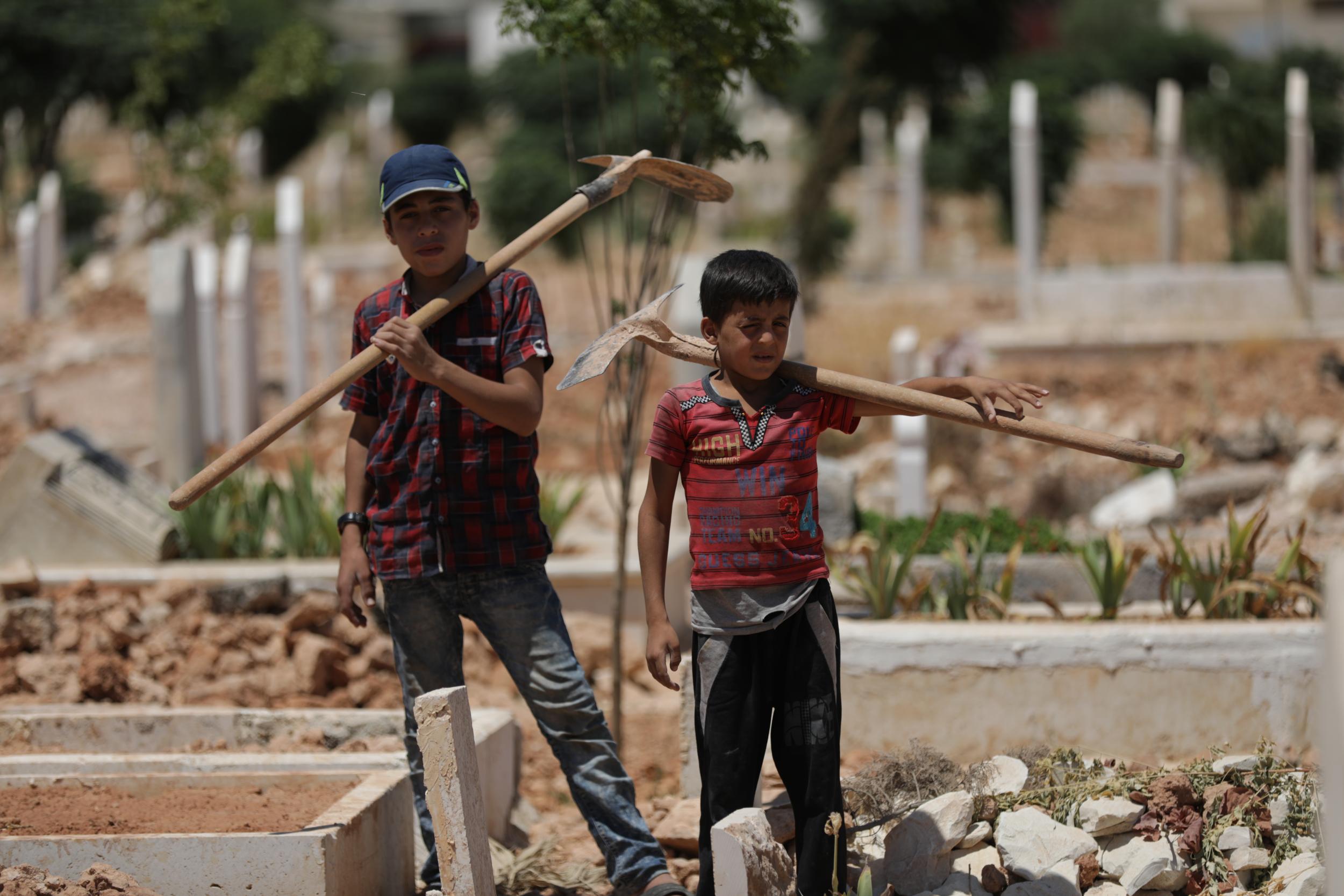 Eight-year-old Jawad* and 15-year-old Yazan pictured in the cemetery where they work as grave diggers. They also clean and water the graves