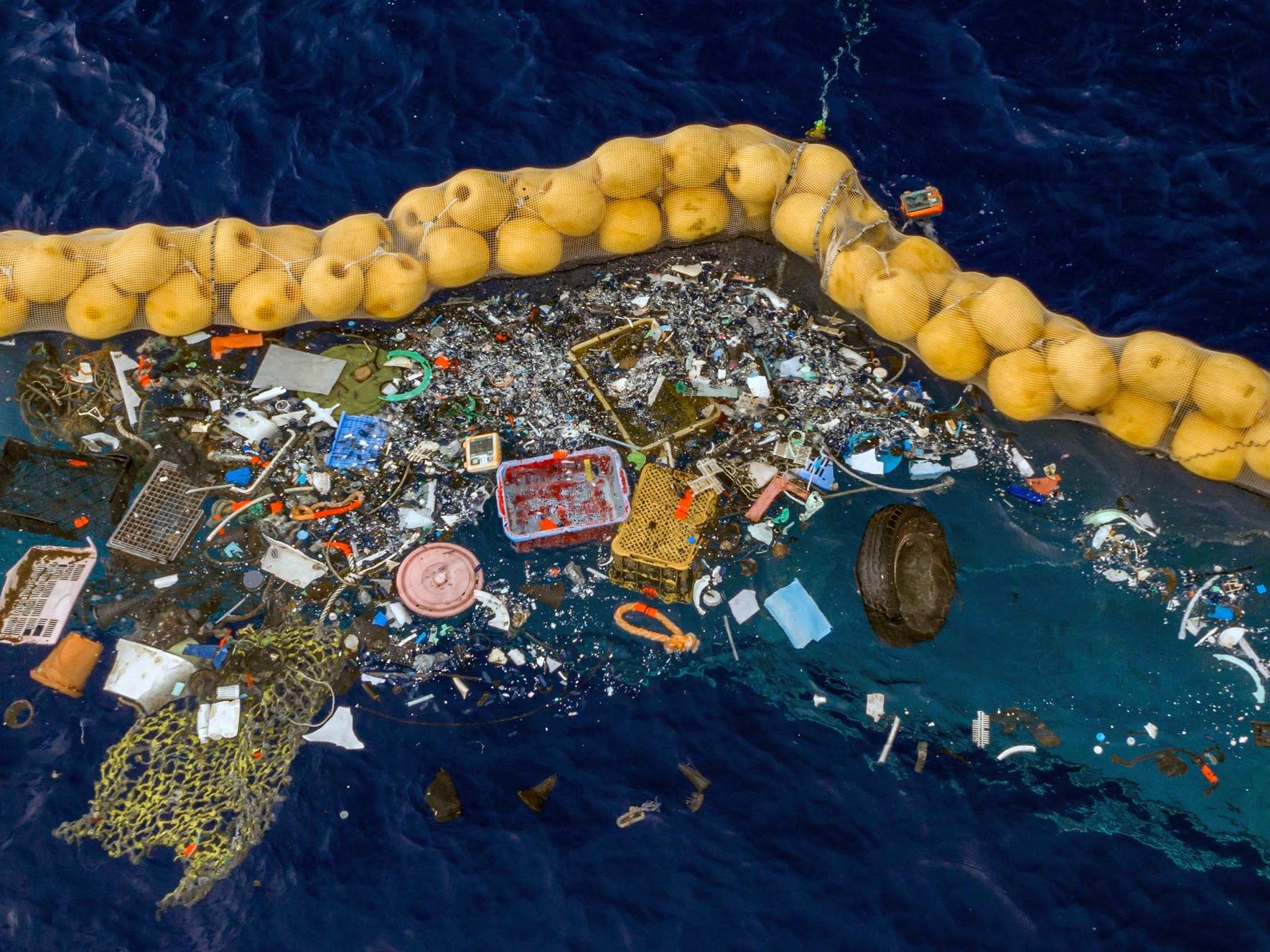 Plastic is retained in front of an extended cork line in the Pacific Ocean by the system designed by Boyan Slat