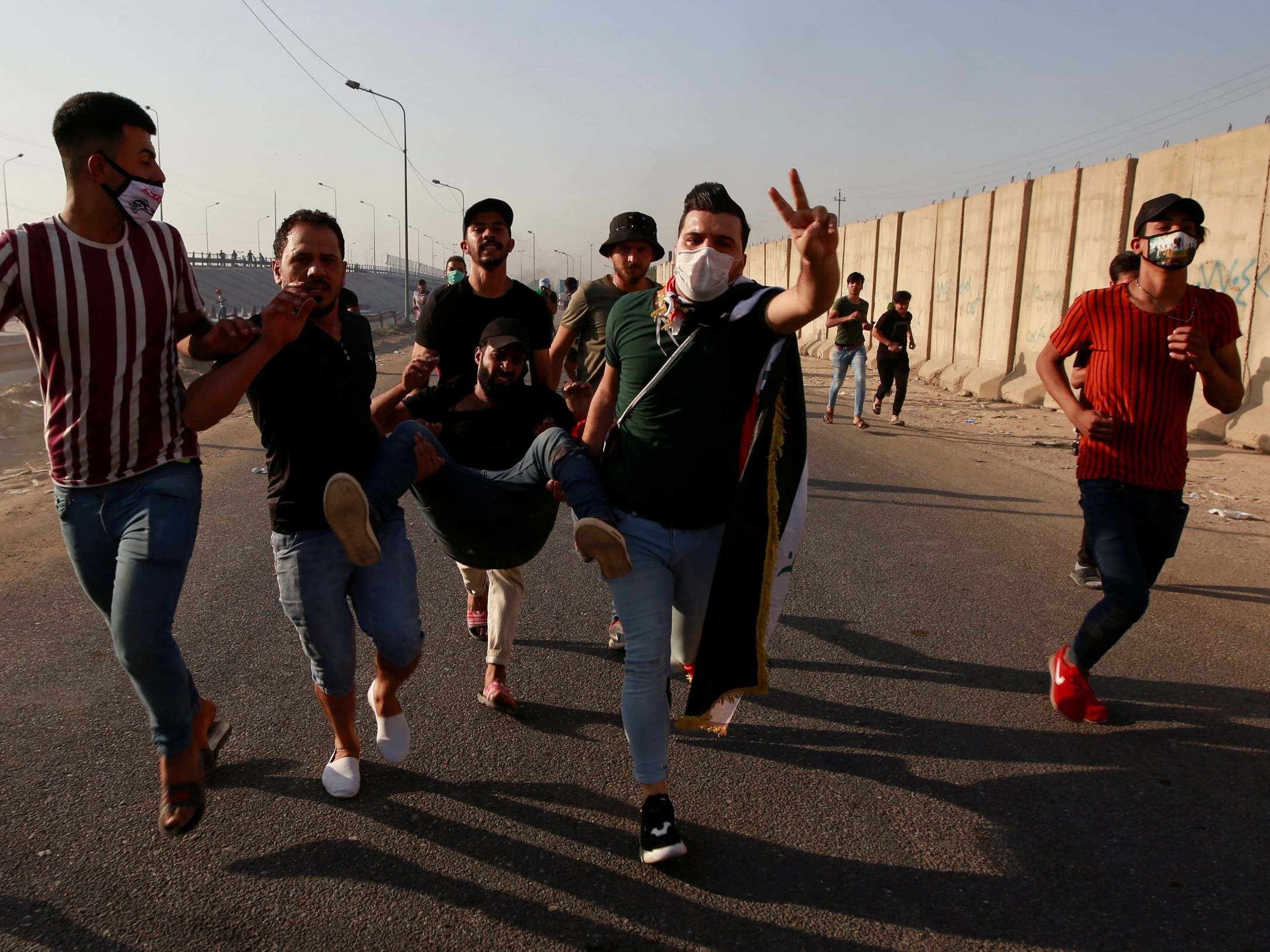 Men carry a demonstrator injured at a protest during a curfew in Baghdad on Thursday