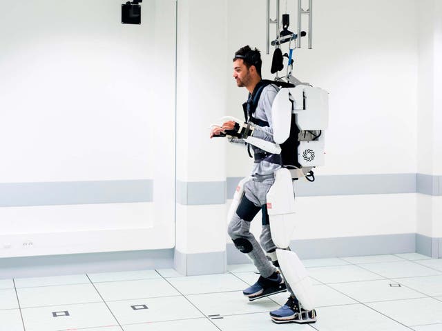 Thibault walks in the robotic suit using a harness for balance