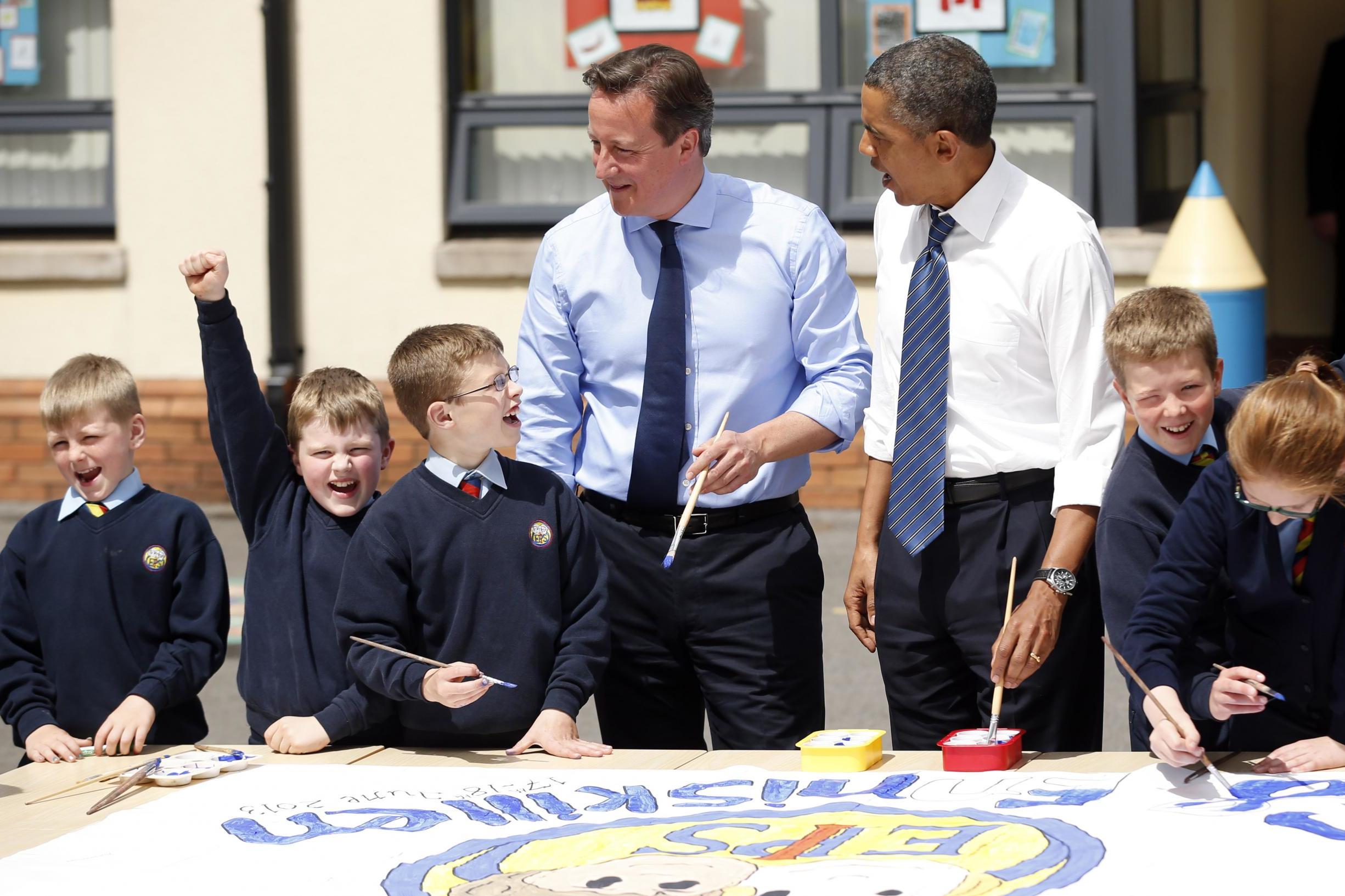 Barack Obama and David Cameron help students on a project about the G-8 summit in 2013 during a visit to the Enniskillen Integrated Primary School (Getty)