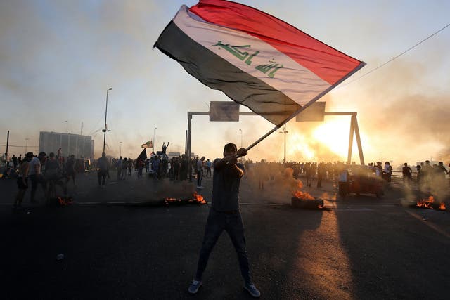 An Iraqi protester waves the national flag during a demonstration against state corruption, failing public services and unemployment