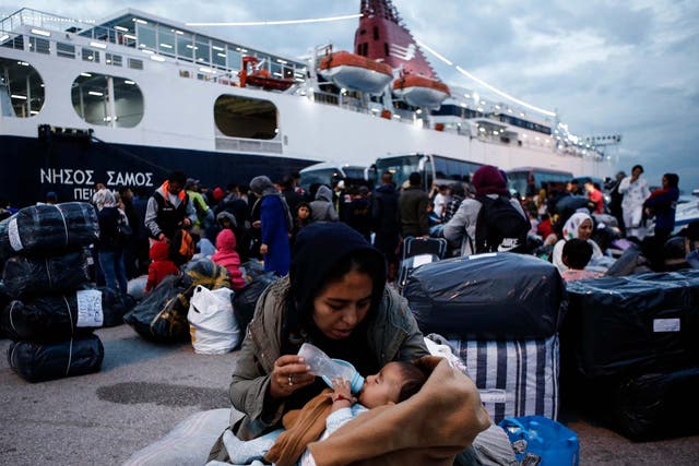 A woman feeds her baby after disembarking from the ferry Nissos Samos upon her arrival from Lesvos island to the Greek port of Piraeus