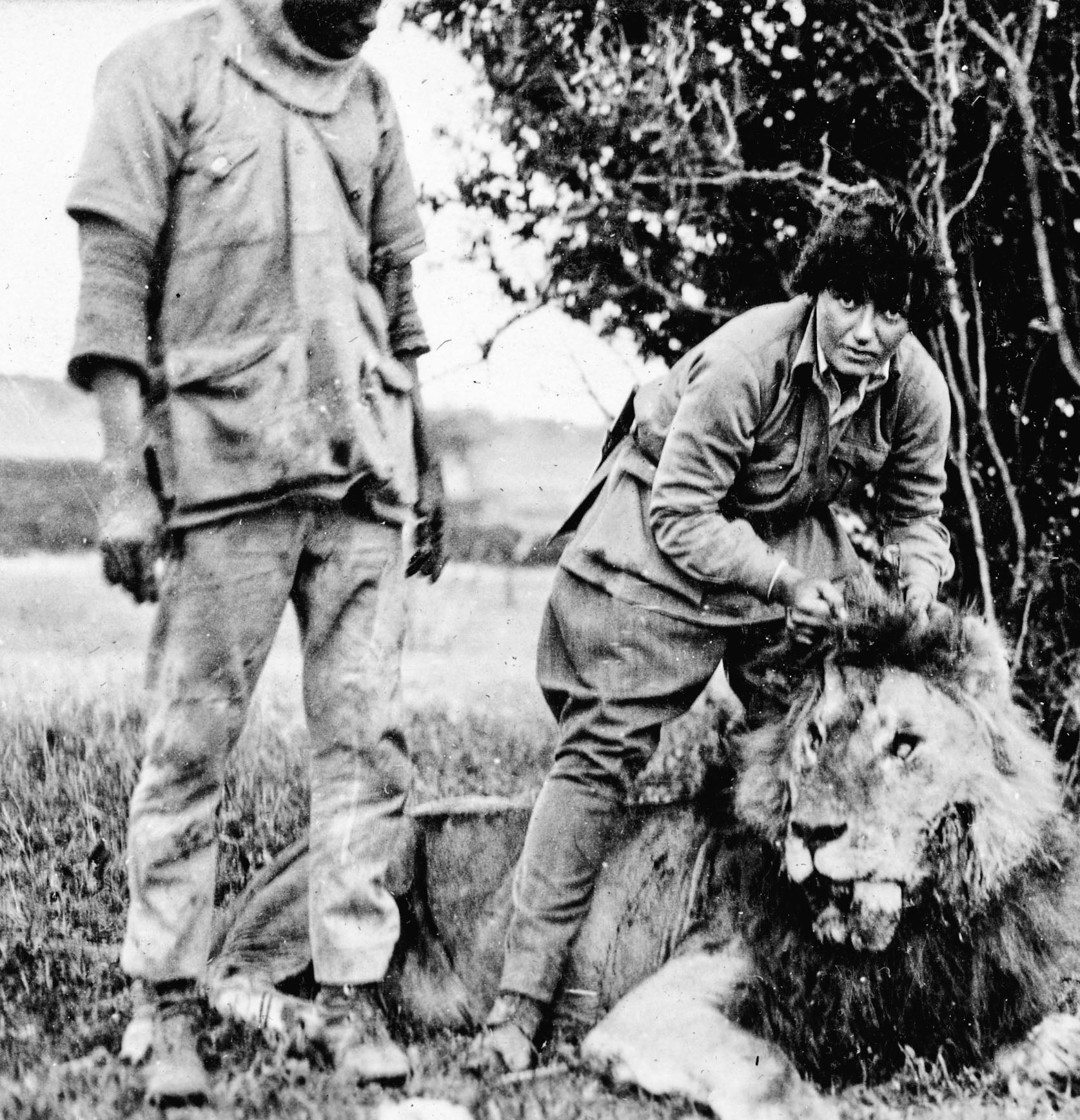 Gertie holds the head of lion with an African guide to her left during a 1927-28 east Africa expedition