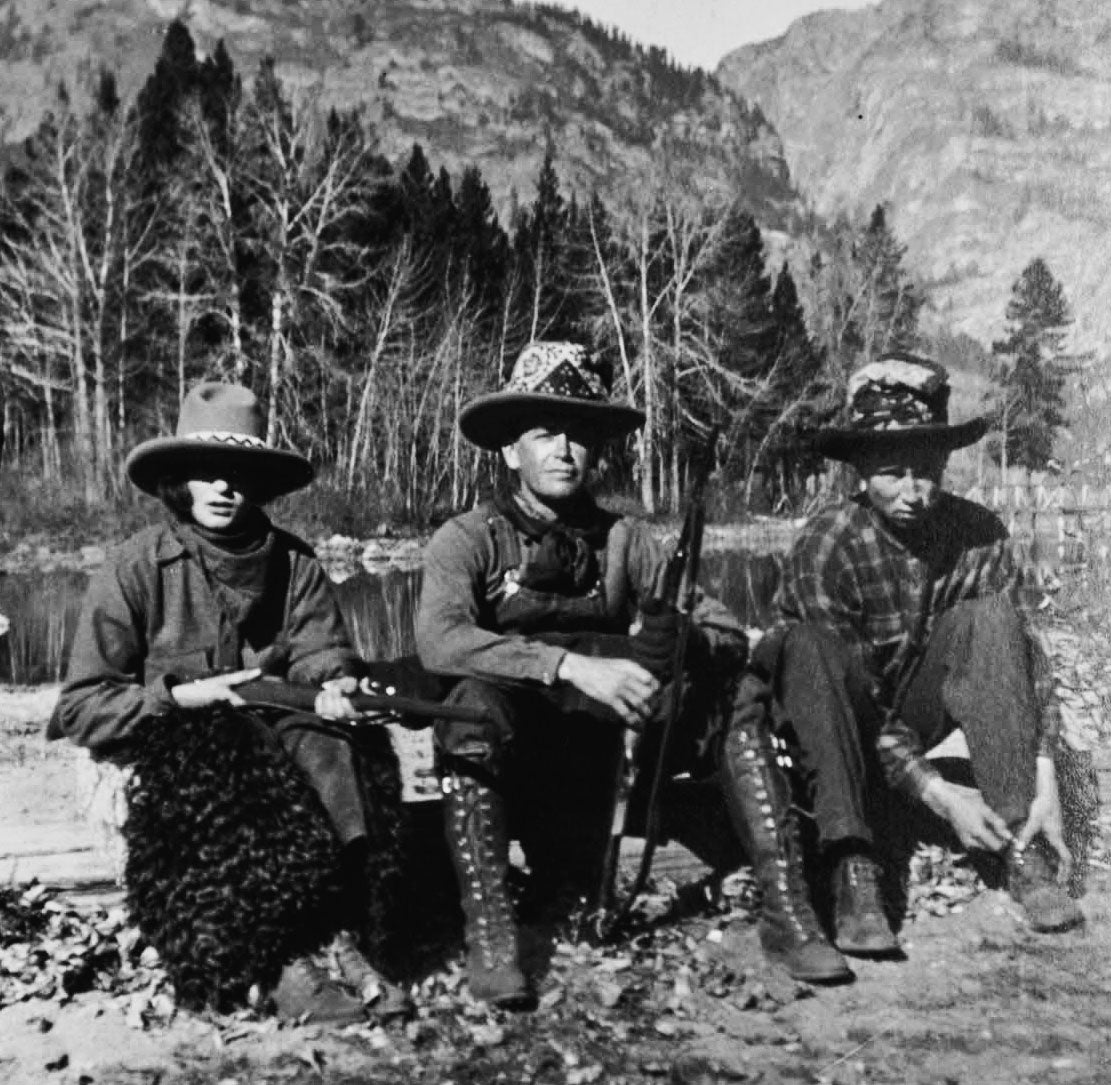 Gertie, wearing a cowboy hat and holding a rifle, is pictured in the Teton Range in Wyoming in the summer of 1920