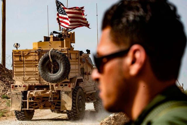 A US soldier sits atop an armoured vehicle during a demonstration by Syrian Kurds against Turkish threats