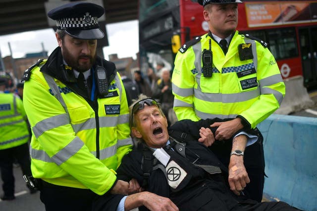 A climate protester is removed by police as Extinction Rebellion tries to block London City airport