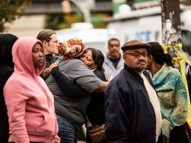 Two people embrace at the scene of a shooting in the Brooklyn borough of New York on Saturday