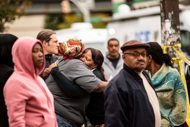 Two people embrace at the scene of a shooting in the Brooklyn borough of New York on Saturday