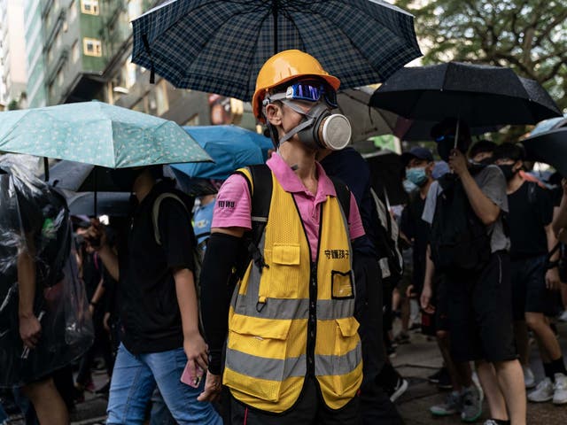 Pro-democracy volunteer stands in front of Tsim Sha Tsui Police Station as protesters march on a street on October 12, 2019 in Hong Kong