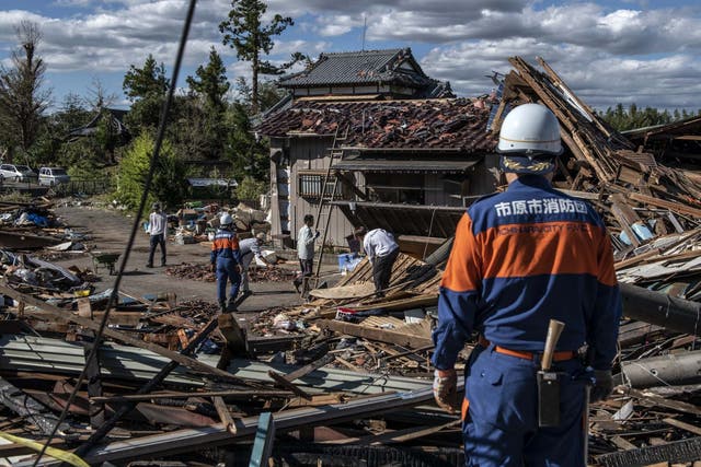 Search and rescue crews sort through the debris of a building destroyed by a tornado shortly before the arrival of Typhoon Hagibis