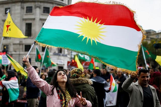 A woman flashes a V-sign as she waves a Kurdish flag during a pro-Kurdish rally against Turkey's military action in northeastern Syria, in London