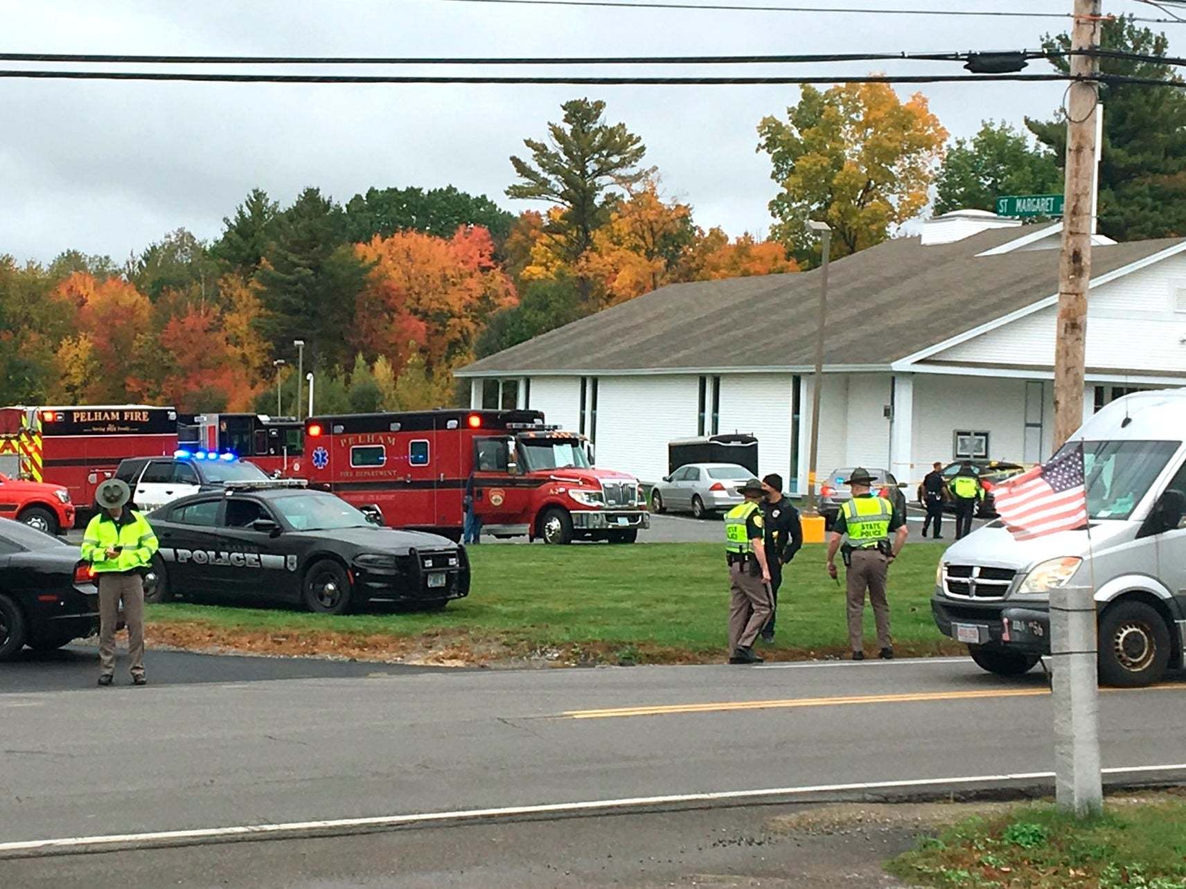 In this photo provided by WMUR-TV, police stand outside the New England Pentecostal Church after a shooting during a wedding on Saturday, 12 October 2019, in Pelham, New Hampshire.