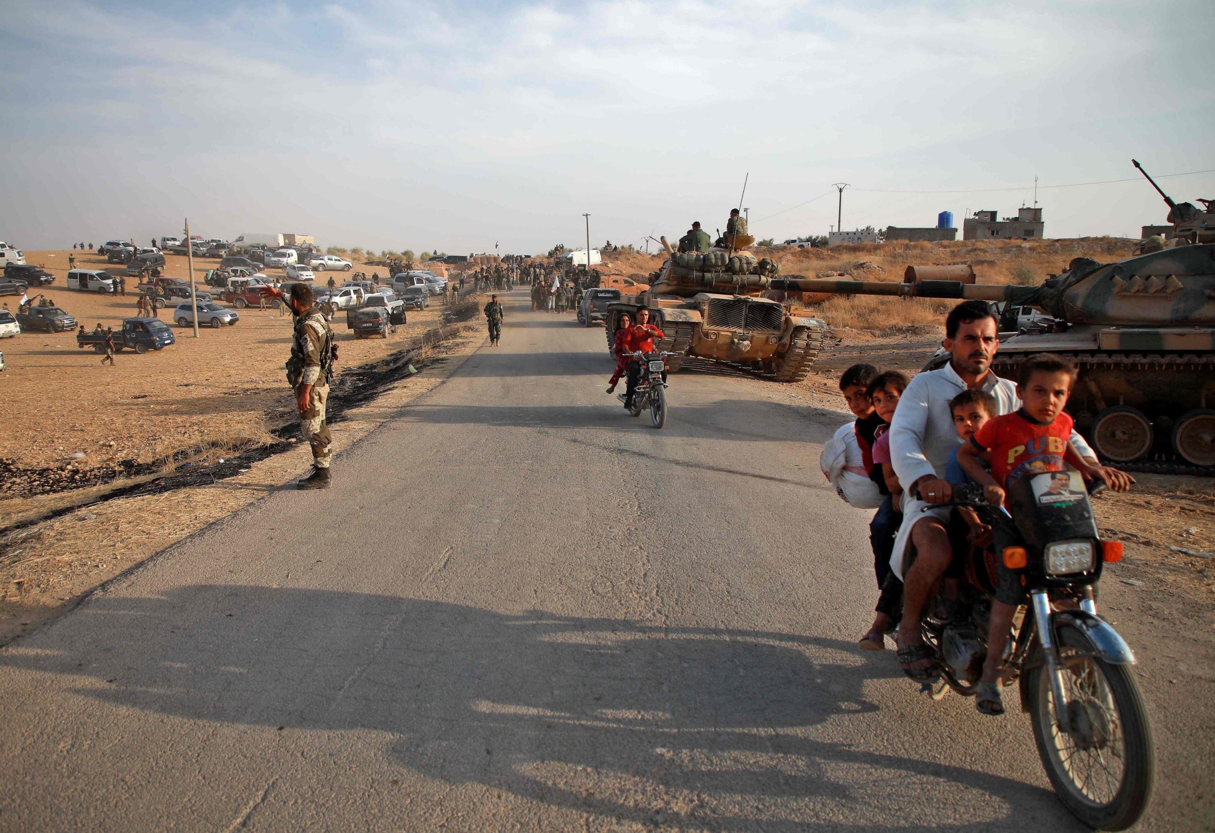 Syrian Arab civilians flee as Turkish troops with American-made M60 tanks and Turkish-backed Syrian fighters gather near the village of Qirata on the outskirts of the northern city of Manbij near the Turkish border on Monday