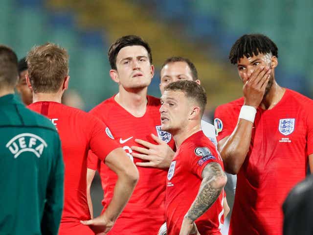 England players wait after the match was stopped for racist chanting