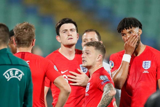 England players wait after the match was stopped for racist chanting