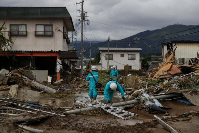 Utility workers survey the damage in a Nagano neighbourhood devastated by Typhoon Hagibis on Tuesday 15 October