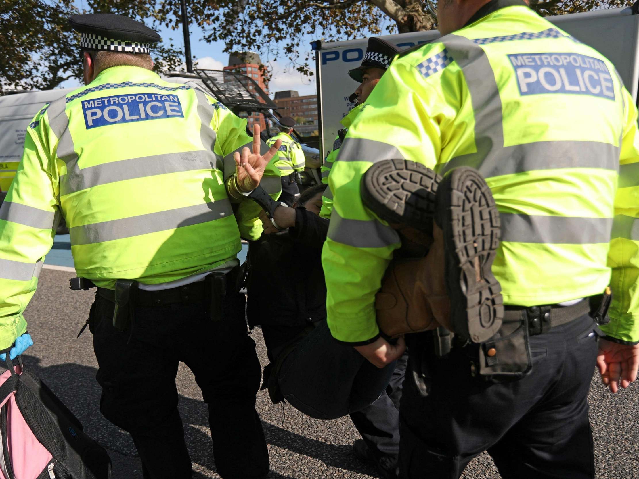 Police officers arrest an activist during a protest on Millbank on Tuesday