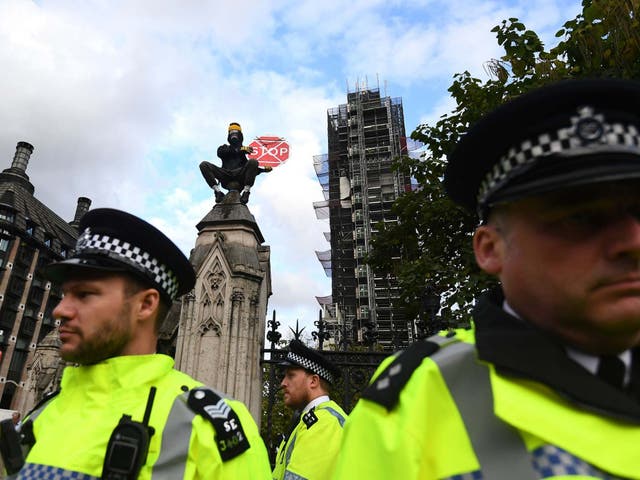 An extinction rebellion protester sits on a pillar in Westminster.