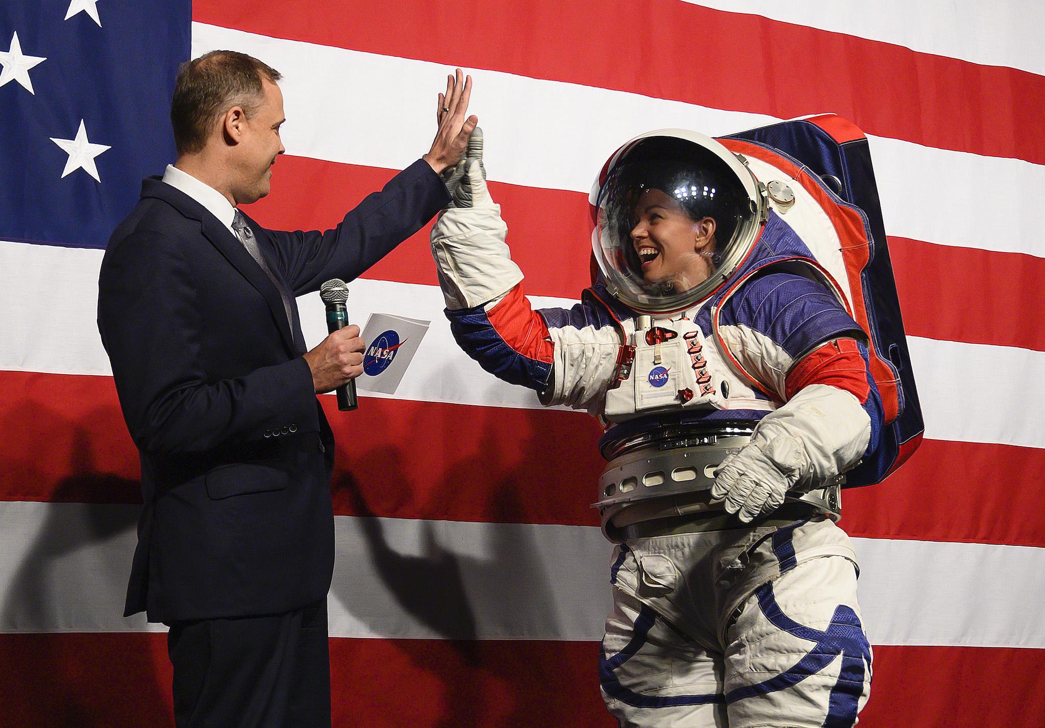 NASA administrator Jim Bridenstine (L) welcomes Advance space suit engineer, Kristine Davis (R), to the stage during a press conference displaying the next generation of space suits as parts of the Artemis program in Washington, DC