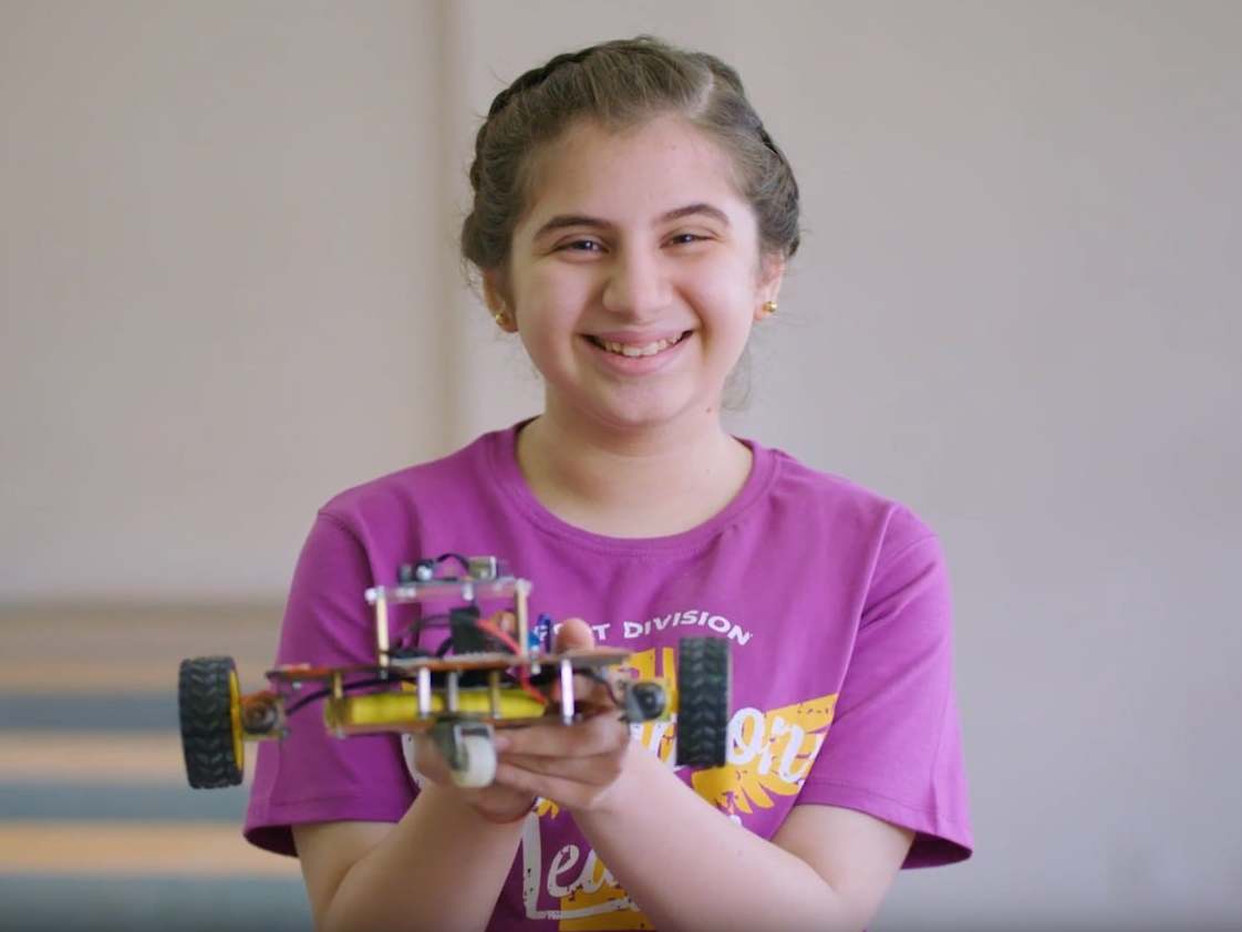 A student holds up a robot she programmed during a LearnOBots workshop