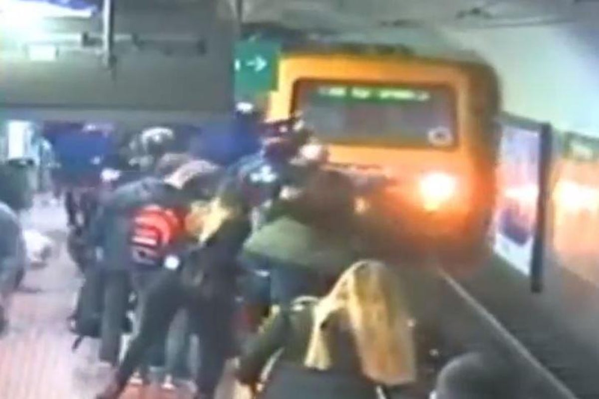 Woman falls onto tracks of approaching train after man faints on her ...