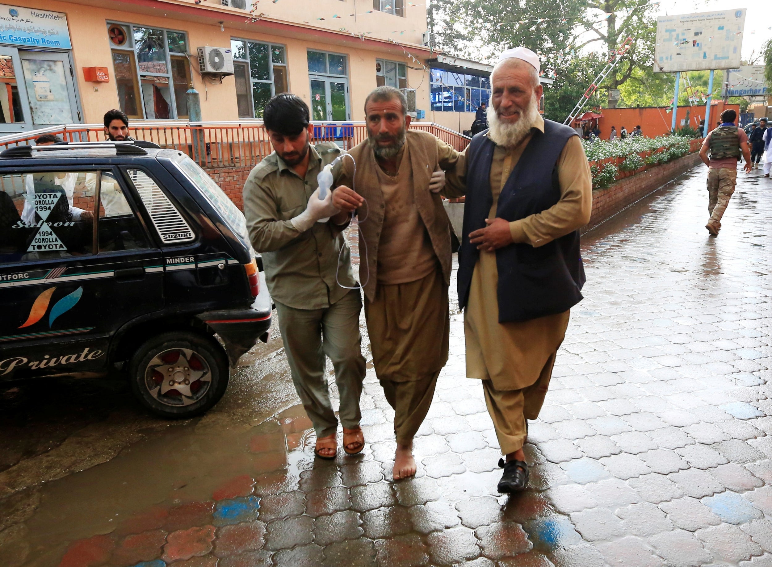 Men carry an injured person to a hospital after the bomb blast rocked the mosque in the Nangarhar Province